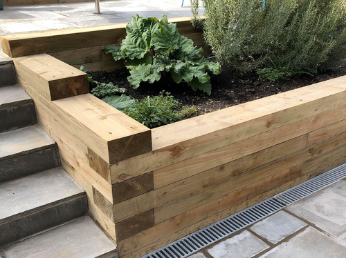 Garden Sleepers 3m (10ft) used in a raised garden bed with leafy plants, showcasing durable timber construction from Newcastle Turf.